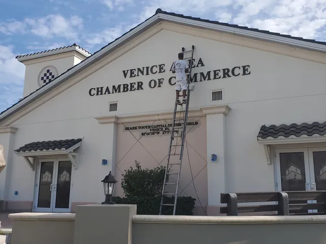Kranenburg Painting crew member on a ladder repainting trim near the entrance of the Venice Area Chamber of Commerce building